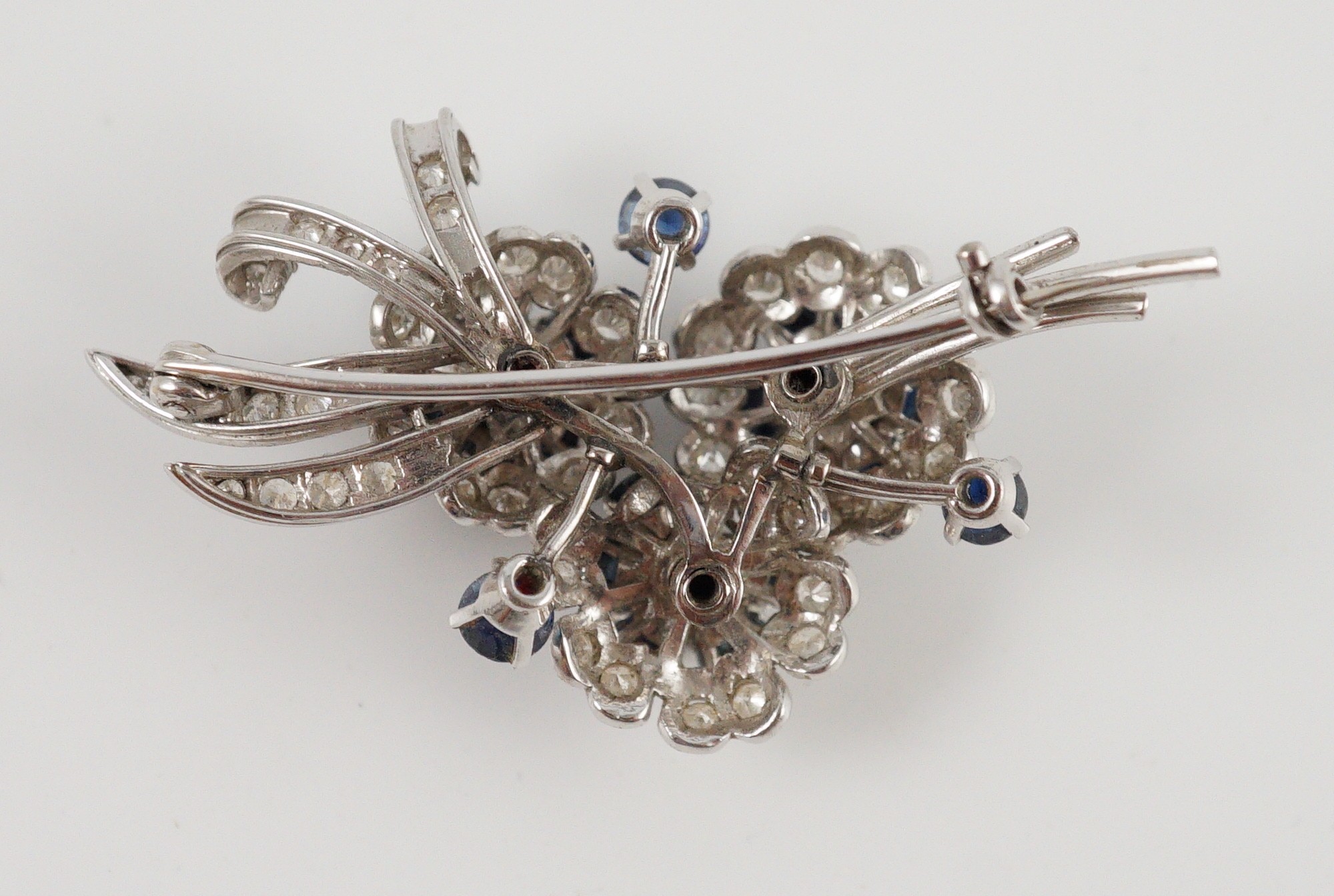A white gold, sapphire and diamond cluster set floral spray brooch